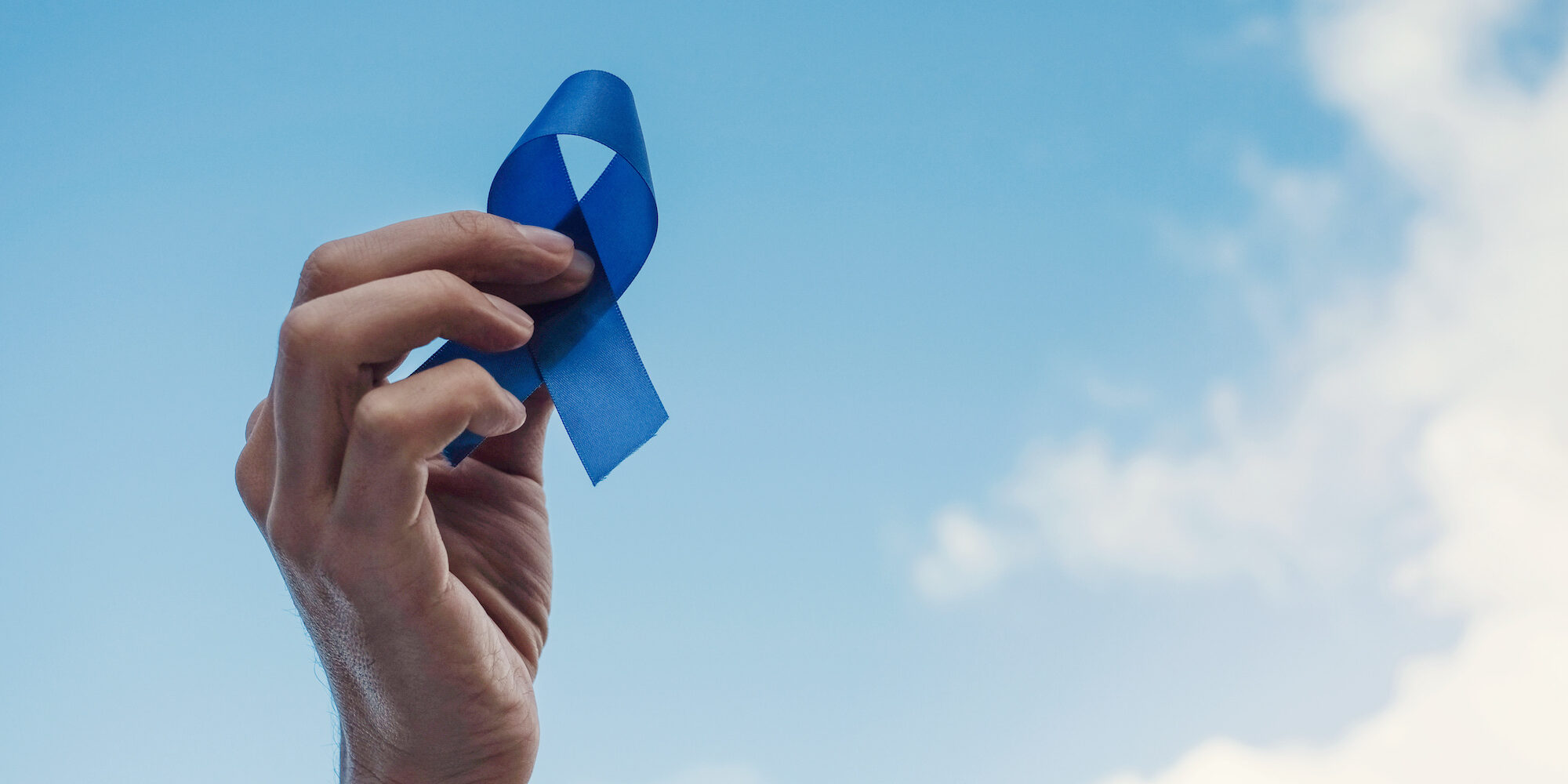 Man Hands holding blue ribbon over blue sky, Prostate Cancer Awareness, November blue, Men health awareness Comprehensive Prostate Cancer Awareness: Recognizing Signs, Symptoms, Prevention Tips, and When to Consult a Urologist