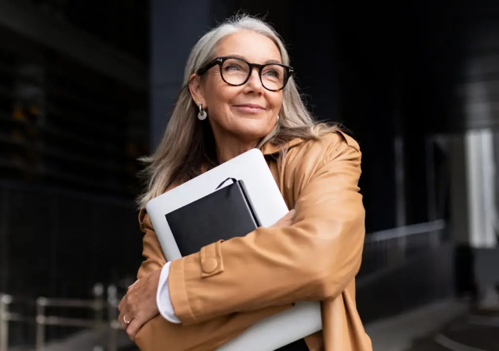 elderly businesswoman with a laptop in glasses outside the office